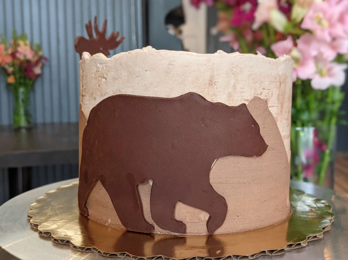 Cake with a silhouette or a bear on it.